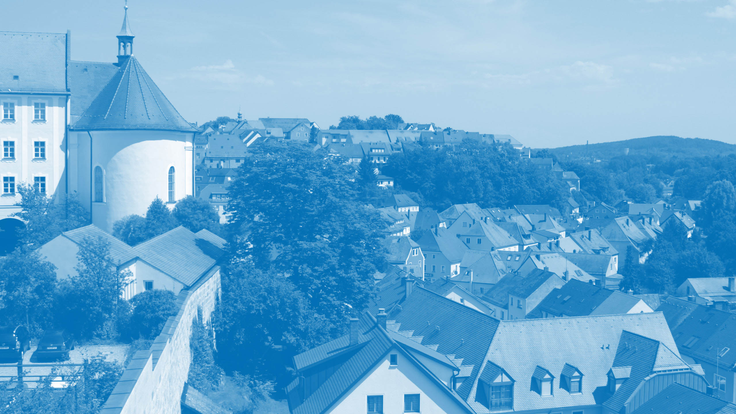 Blick über die Dächer einer bayerischen Kleinstadt bei sommerlichem Wetter symbolisiert den Markenwert „Verantwortung“ von Oberpfalz Medien.